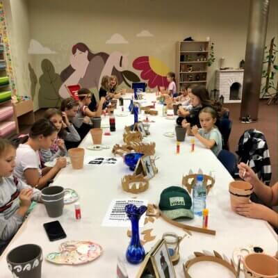 – Dzieci siedzące przy stole malują doniczki w stylu antycznym. Dzieci wykonują wazy w stylu czarnofigurowym. kliknięcie powoduje powiększenie zdjęcia