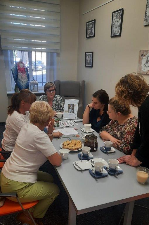 Uczestniczki spotkania pochylone nad stołem studiują schematy.