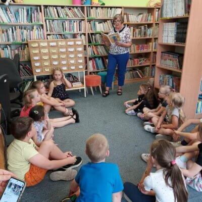 Opowiadania z książki pt. „Biuro Zagubionych Zabawek” Iwony Czarkowskiej czyta dzieciom siedzącym na dywanie Elżbieta Wach, emerytowana bibliotekarka. Kliknięcie w obrazek spowoduje powiększenie.