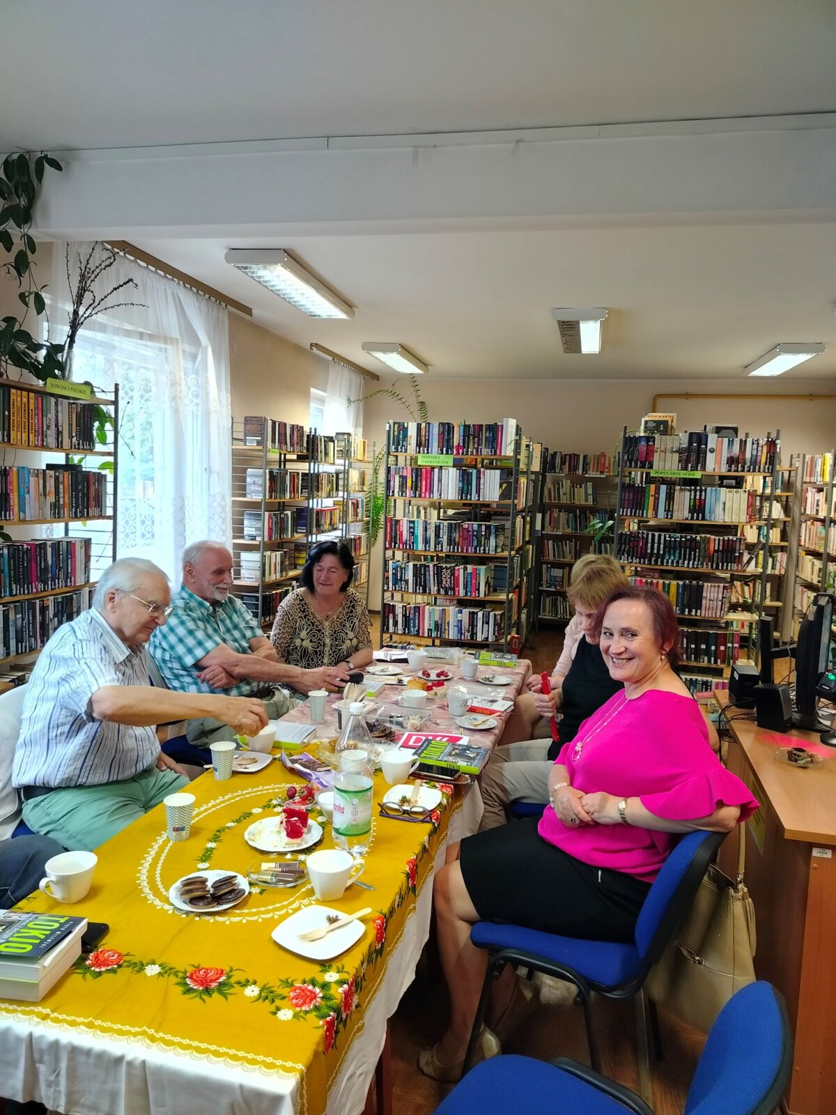 Uczestnicy DKK przy stole z poczęstunkiem, gadżetami DKK i książkami „Tokio. Opowieści z Dolnego Miasta” Piotra Milewskiego.