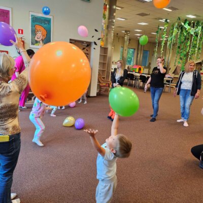 Dzieci i opiekunowie bawią się balonami. Kliknięcie powoduje powiększenie zdjęcia.