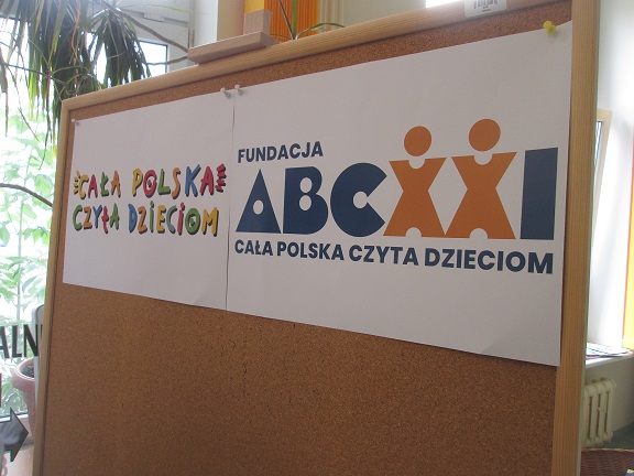 Tablica korkowa z wywieszonym logiem akcji „Cała Polska Czyta Dzieciom” i logiem „Fundacja ABCXI Cała Polska Czyta Dzieciom”