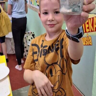 Chłopiec pokazuje swój słoiczek z minerałami. Kliknięcie powoduje powiększenie zdjęcia.