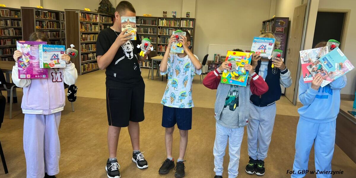 Szóstka dzieci prezentuje książki podczas zajęć w pomieszczeniu biblioteki.