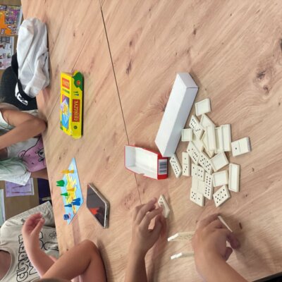 Dzieci grają przy stole w gry domino i chińczyk. Kliknięcie powoduje powiększenie zdjęcia.
