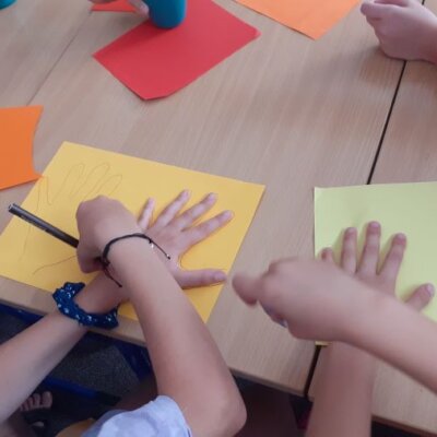 Dzieci odrysowują dłonie, z których powstanie ogon smoka. Kliknięcie powoduje powiększenie zdjęcia.
