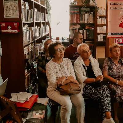 Wnętrze biblioteki. Po lewej Janusz Dreczka prowadzący spotkanie literackie o Miłoszu, na wprost część uczestników wydarzenia. Kliknięcie powoduje powiększenie zdjęcia.