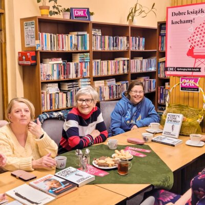 Biblioteka. Trwa DKK. Sześć kobiet siedzi przy stole. Dyskutują. Część z nich się śmieje. Na stole książki o Młynarskim, zakładki. Kliknięcie w obrazek spowoduje powiększenie obrazu.