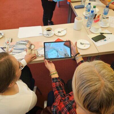 Bibliotekarki oglądają przy pomocy tabletu książkę w rozszerzonej rzeczywistości. Kliknięcie powoduje powiększenie zdjęcia.