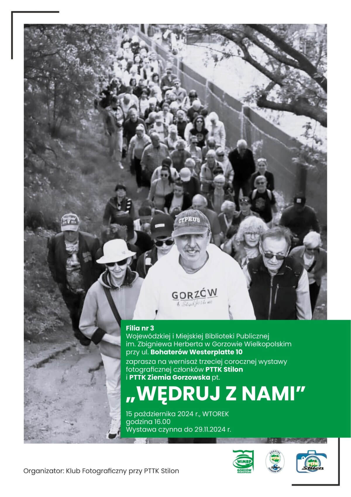 Plakat promujący wydarzenie "Wędruj z nami" ze zdjęciem grupowym członków PTTK na czarno-białym tle.