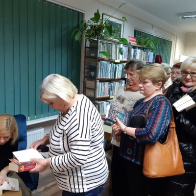 Autorka Barbara Wysoczańska podpisuje książki. W tle uczestniczki spotkania. Kliknięcie w obrazek spowoduje powiększenie.