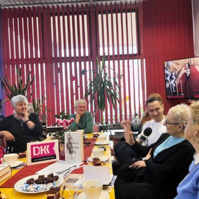 Grupa osób siedzi przy stole i uczestniczy w spotkaniu DKK. Kliknięcie w obrazek spowoduje powiększenie.