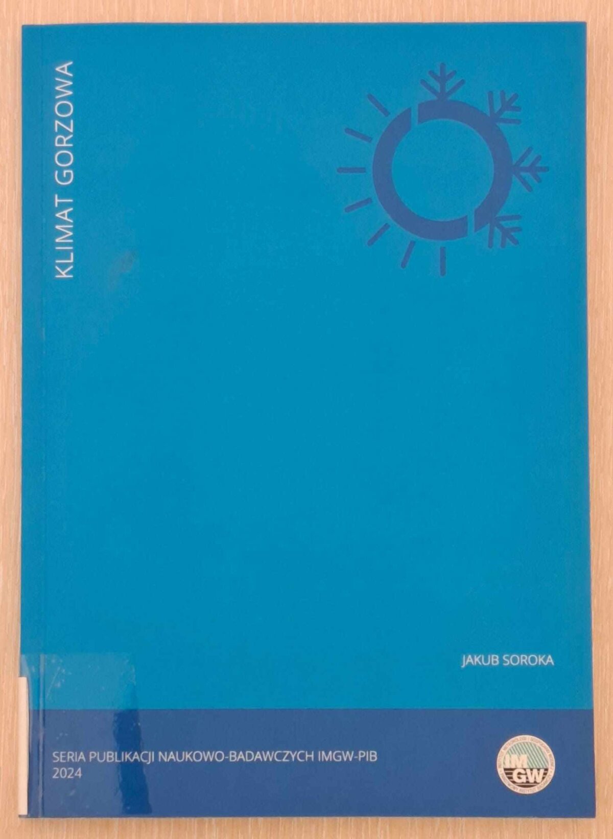 Zdjęcie przedstawia niebieską okładkę książki pt. Klimat Gorzowa autorstwa Jakuba Soroki. Na okładce znajduje się minimalistyczna grafika symbolizująca słońce i śnieżynkę, sugerująca tematykę klimatyczną. W dolnej części widnieje informacja: 'Seria publikacji naukowo-badawczych IMGW-PIB 2024' wraz z logotypem IMGW.