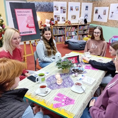 Klubowiczki wraz z bibliotekarką siedzą przy stole i dyskutują o książce. Kliknięcie w obrazek spowoduje powiększenie.