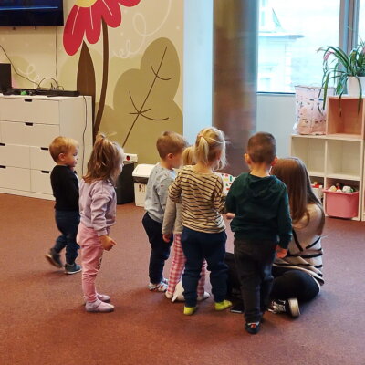 Dzieci z zainteresowaniem przyglądają się książce, którą czyta im bibliotekarka. Kliknięcie w obrazek spowoduje powiększenie.