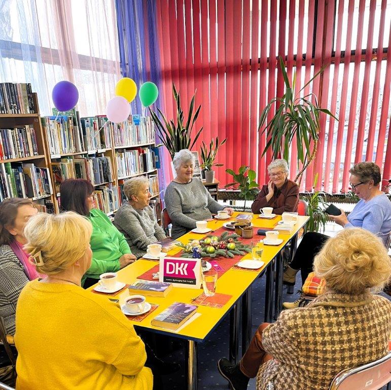 osiem kobiet siedzi przy stole i rozmawiają.